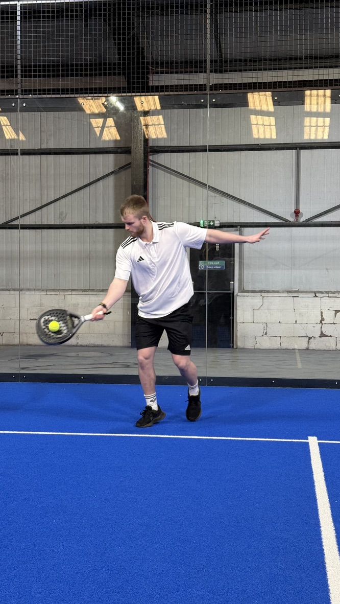 Taylor demonstrating a shot on the blue padel court